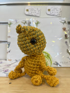 Suzie's Sunshine Dolls Gertrude the Green Ant crochet toy, yellow-green yarn body, black eyes, antennae, and stitched smile.