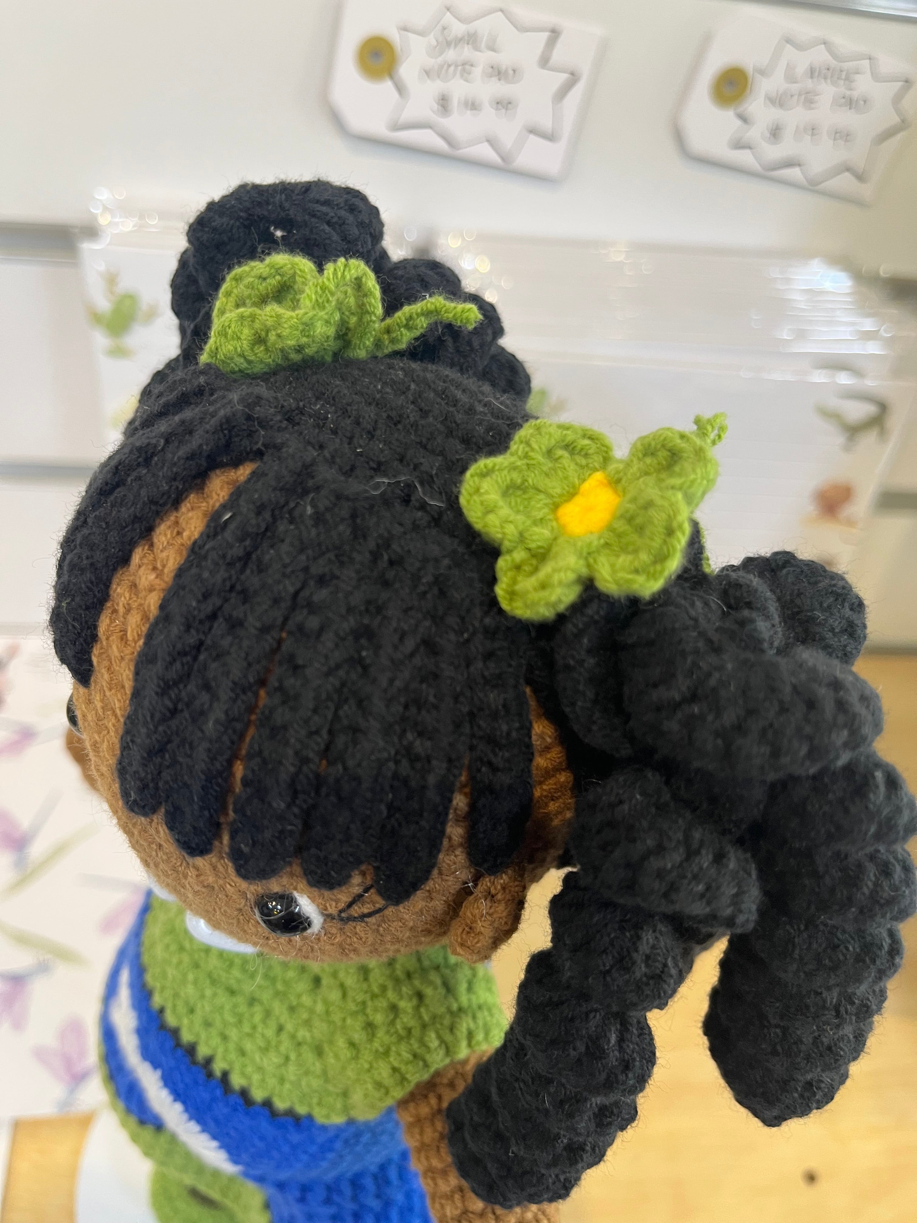 Suzie's Sunshine Dolls handmade doll Leilani with long black curly hair, green and blue flag dress, and green floral accents.