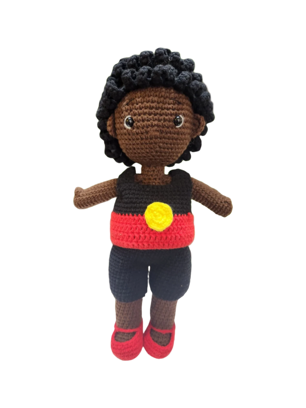 Suzie's Sunshine Dolls Coen, a crochet Indigenous Australian doll with short curly hair, wearing a red, yellow, and black outfit.