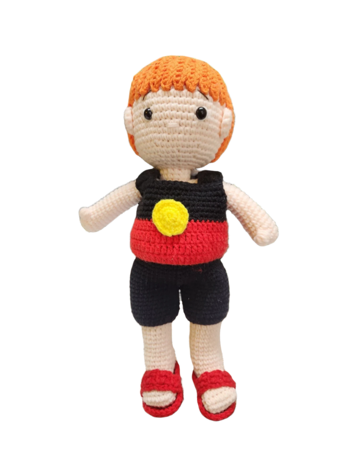 Suzie's Sunshine Dolls Coen, a crochet Indigenous Australian doll with short orange hair, wearing red, black, and yellow outfit.