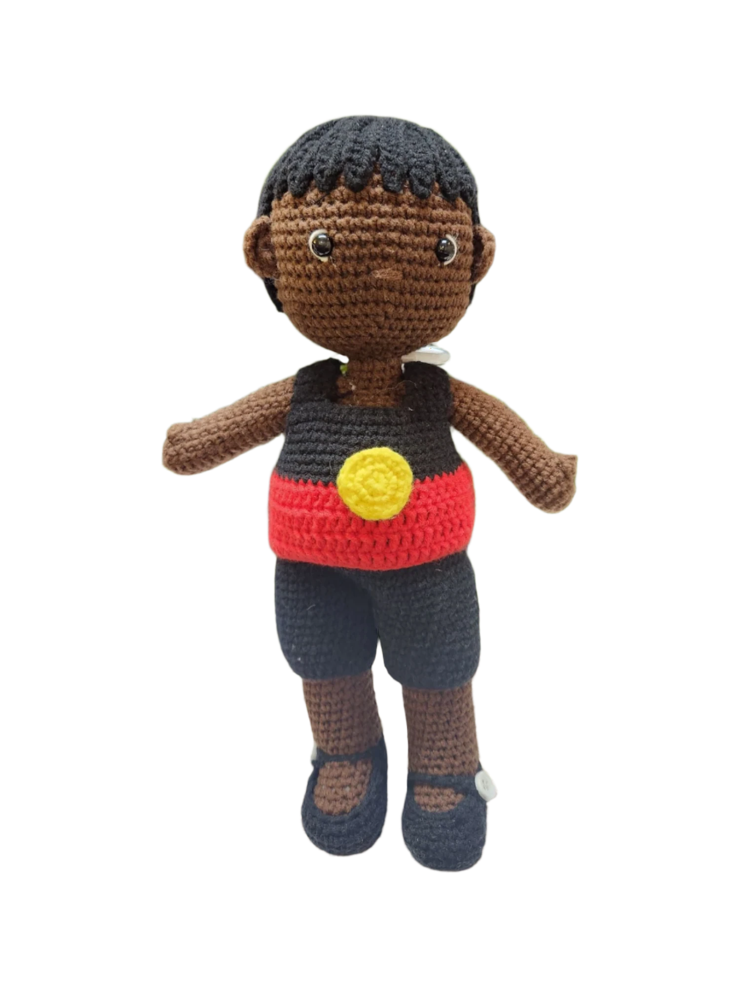 Suzie's Sunshine Dolls Coen, a crochet Indigenous Australian doll with short black hair, wearing a red, yellow, and black outfit.