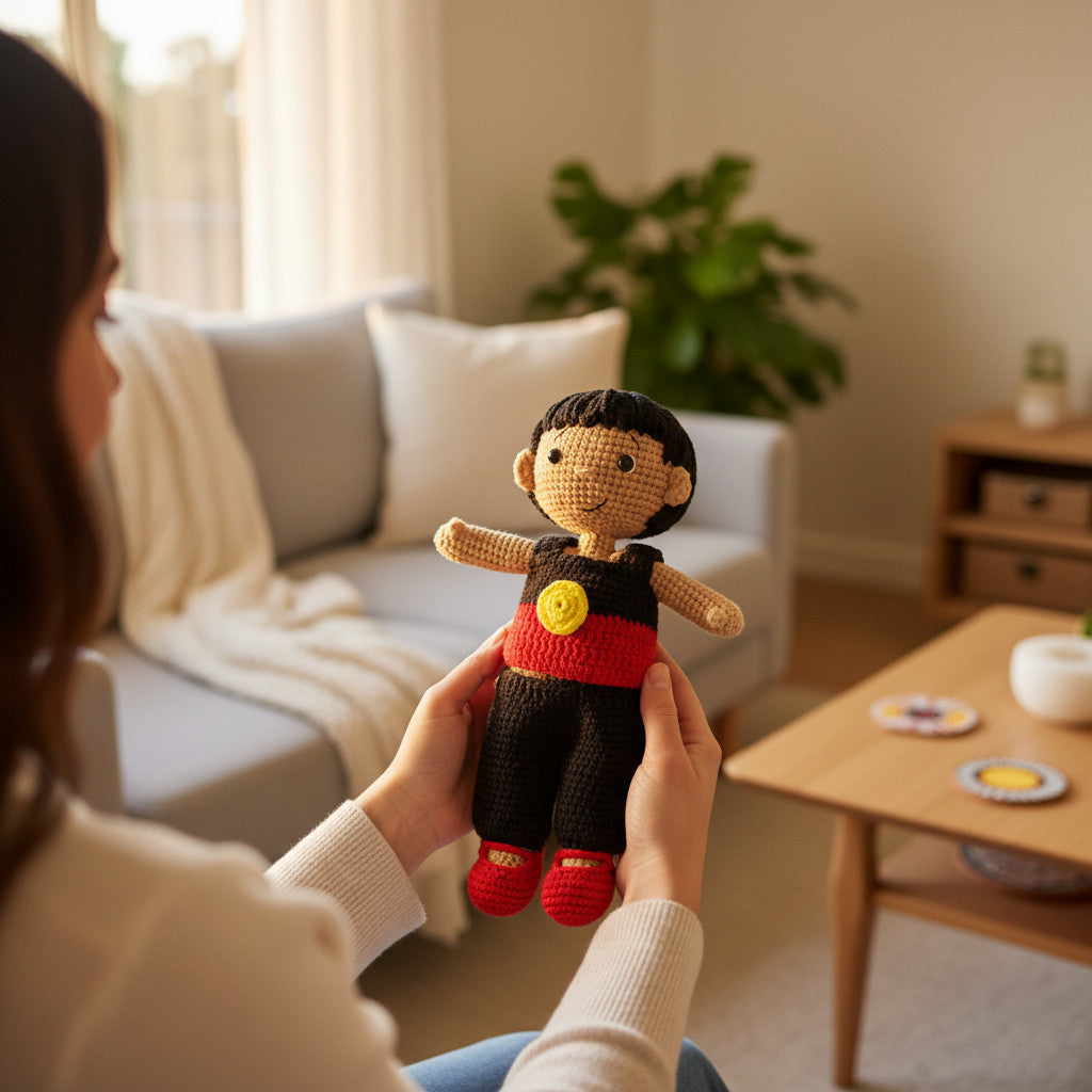 Suzie's Sunshine Dolls Coen, a crochet Indigenous Australian doll with short black hair, wearing red, black, and yellow outfit.