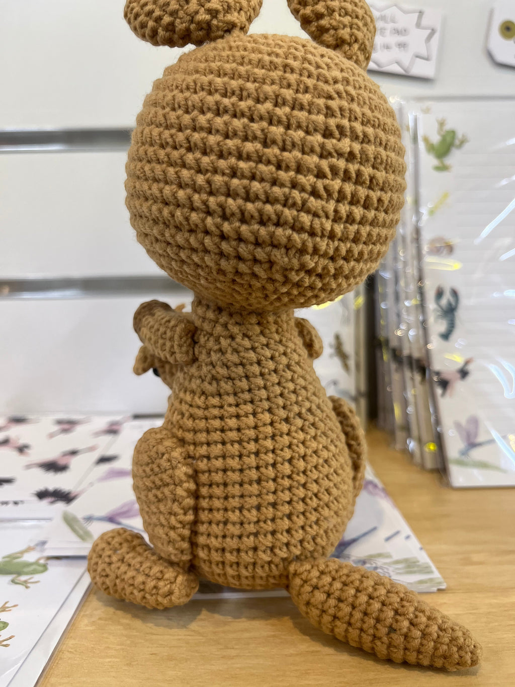 Suzie's Sunshine Dolls Kirsty the Kangaroo, a handmade crochet toy in soft brown yarn with a joey peeking from her pouch.