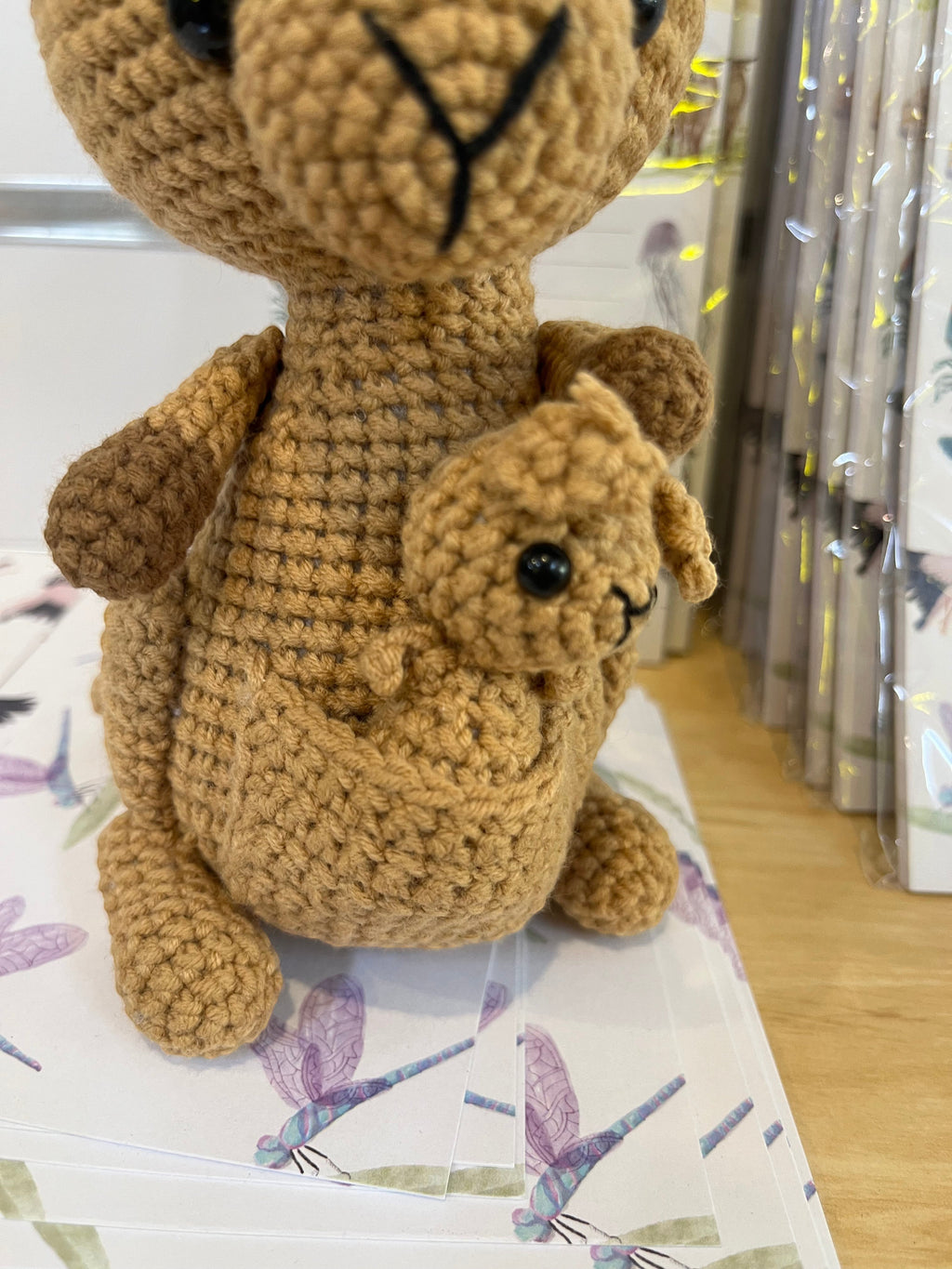 Suzie's Sunshine Dolls Kirsty the Kangaroo, a handmade crochet toy in light brown yarn with a joey in her pouch.