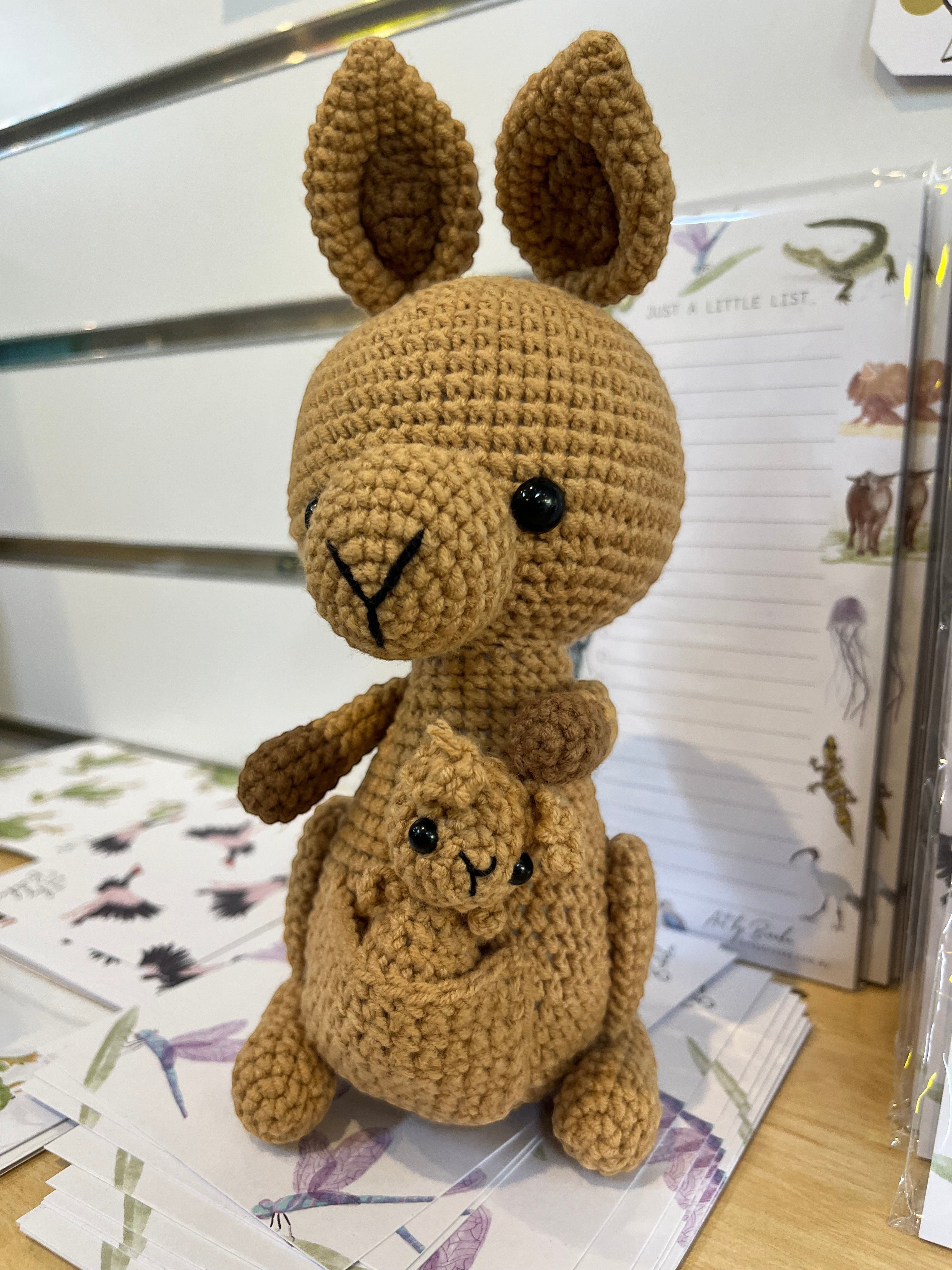 Suzie's Sunshine Dolls Kirsty the Kangaroo, a handmade crochet toy in tan yarn with a joey in her pouch. Features large ears and black button eyes.