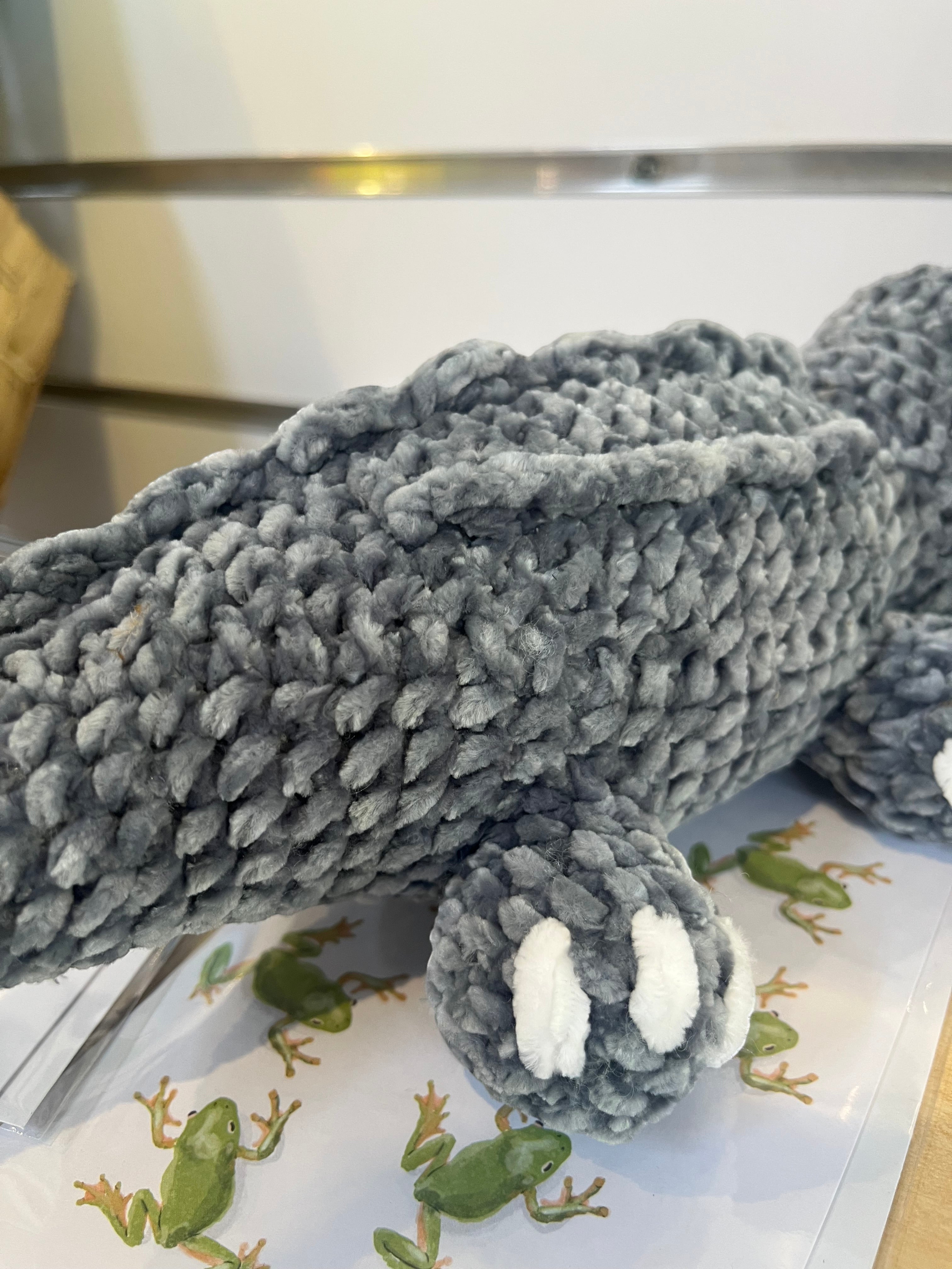 Suzie's Sunshine Dolls Kurtis the Croc, a grey crocheted plush toy with white toes and a stitched smile.
