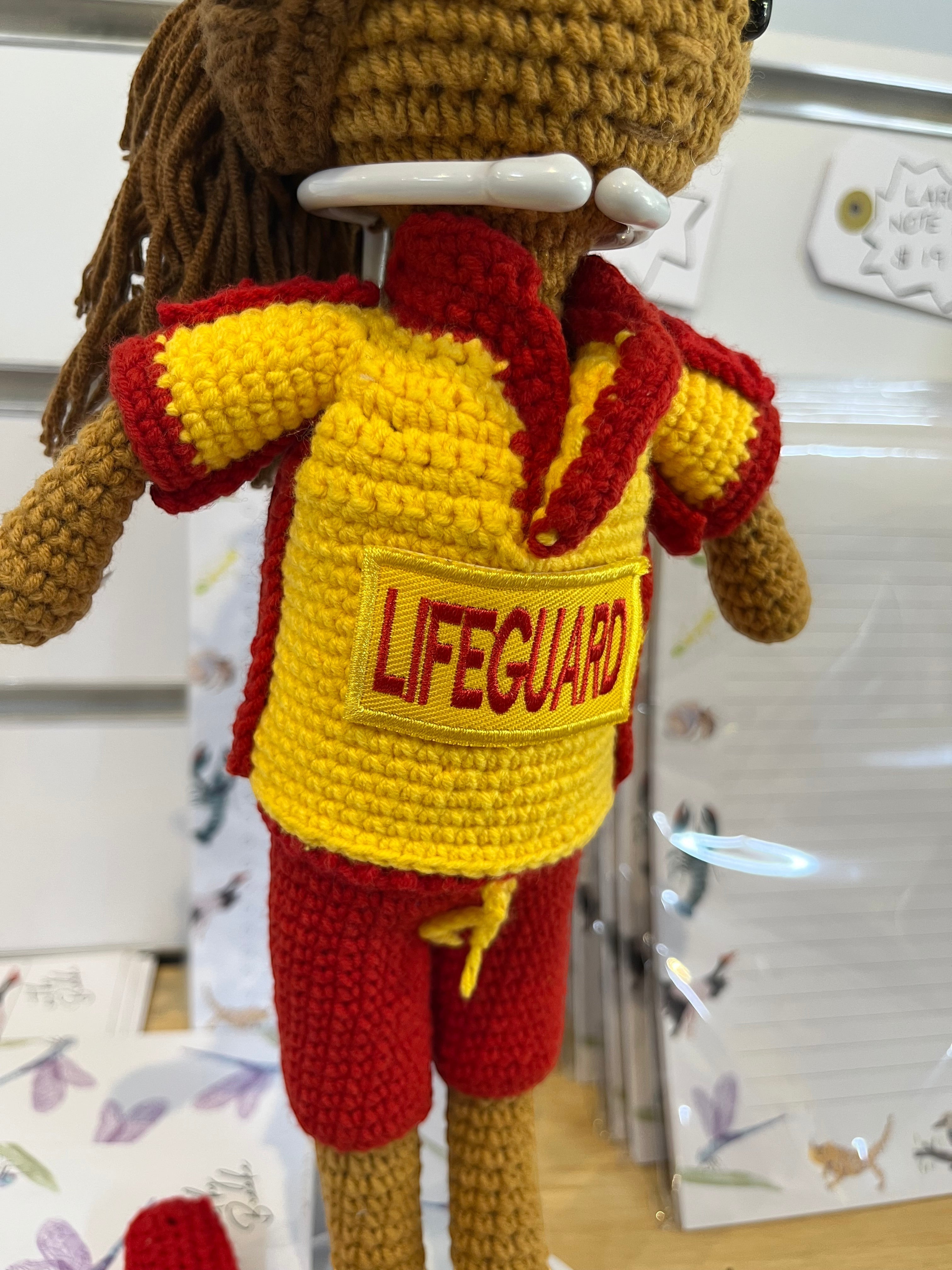 Suzie's Sunshine Dolls crocheted surf lifesaver doll in red shorts and yellow rashie with "LIFEGUARD" patch.