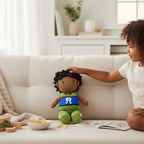 Suzie's Sunshine Dolls Malakai, a crocheted doll with short black hair, wearing green shorts and a blue top with white Dhari headdress detail.
