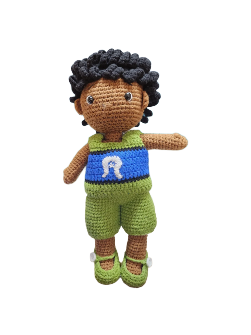 Suzie's Sunshine Dolls Malakai, a crocheted doll with short black hair, wearing green shorts and a blue top with a white Dhari headdress detail.