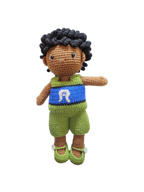 Suzie's Sunshine Dolls Malakai, a crocheted doll with short black hair, wearing green shorts and a blue top with a white Dhari headdress detail.