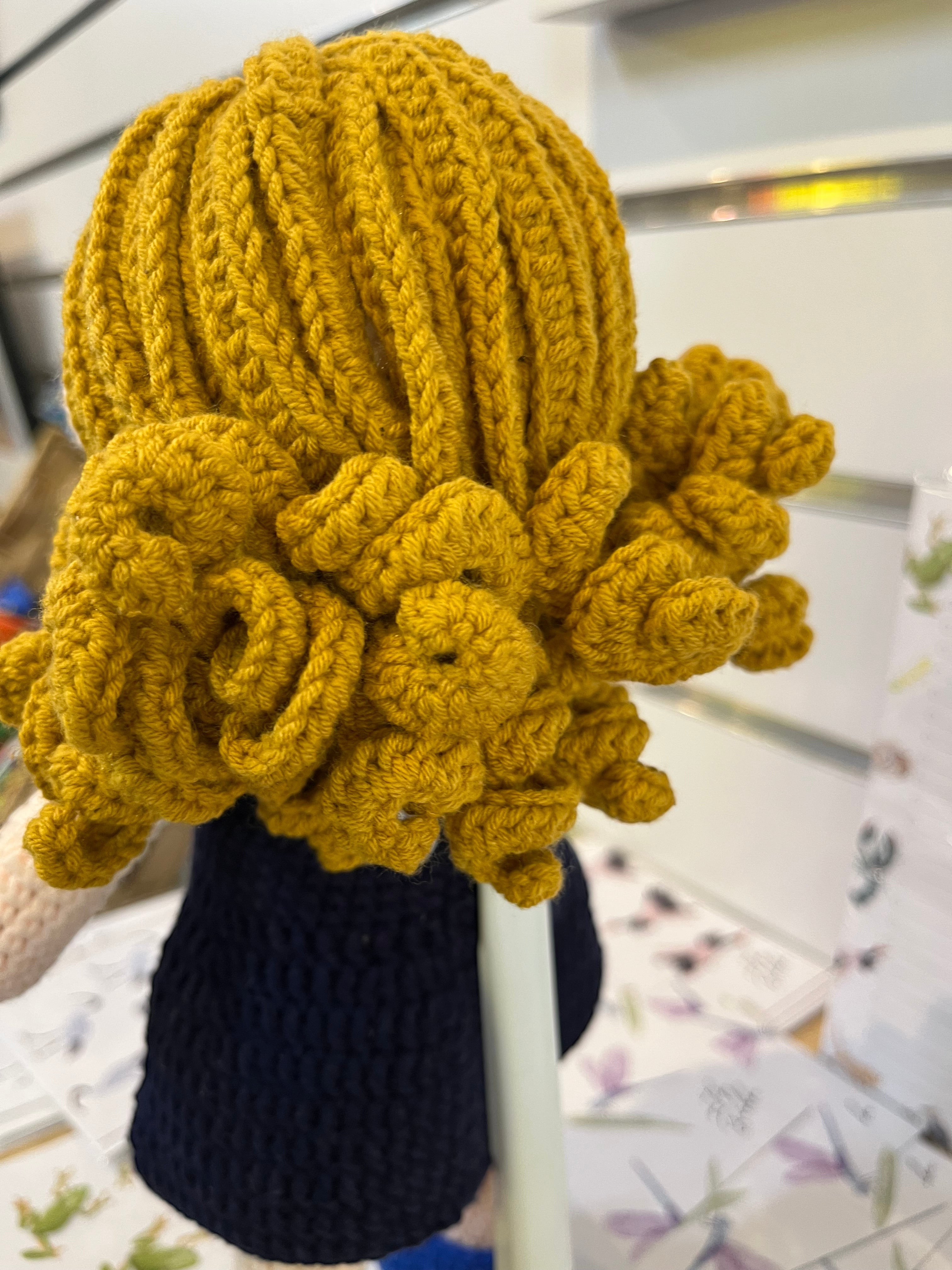 Suzie's Sunshine Dolls hand-crocheted doll in navy with yellow yarn hair and Cancer Council NT patch detail.