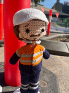 Suzie's Sunshine Dolls orange hi-vis miner/tradie doll, crocheted with navy and grey stripes. White cap.