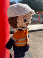 Suzie's Sunshine Dolls orange hi-vis miner/tradie doll, crocheted with navy blue pants and sleeves, and an orange and grey striped top.