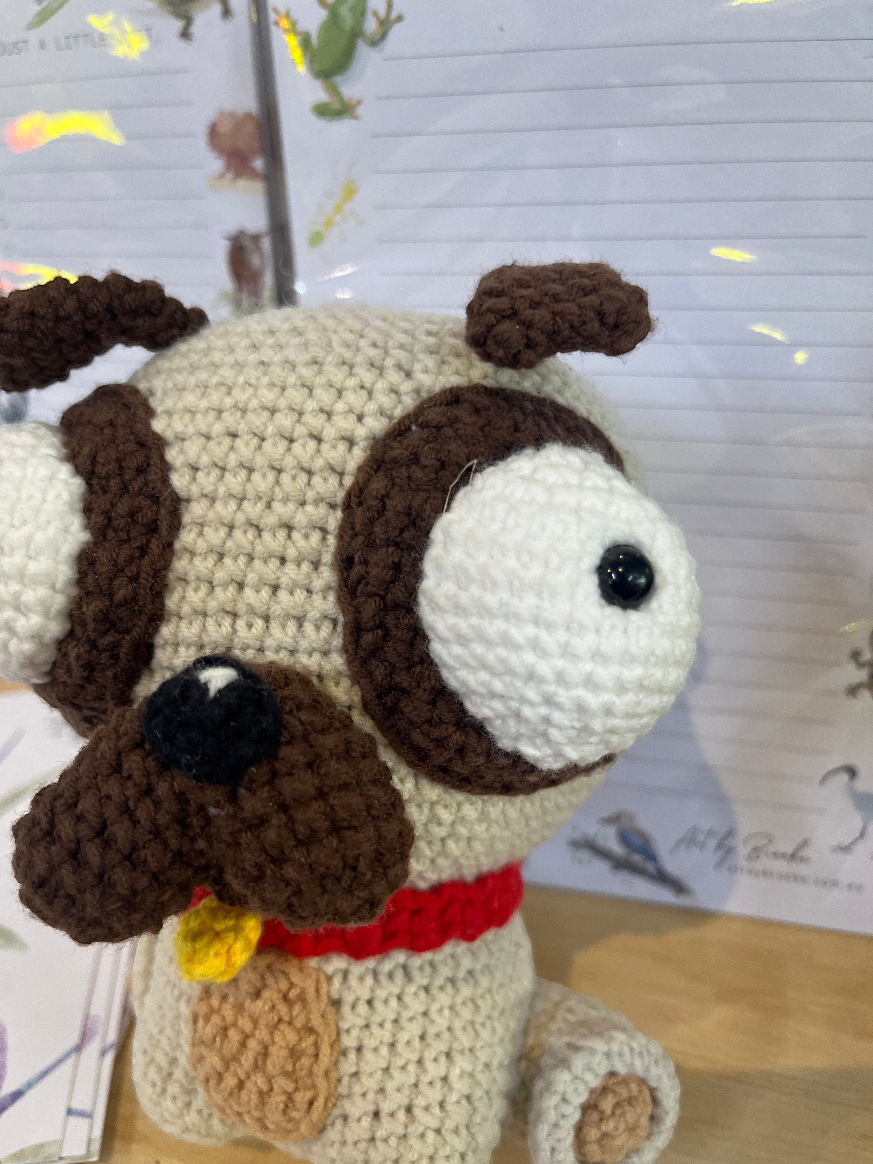 Suzie's Sunshine Dolls Pig the Pug crochet toy. Cream and brown pug with big white eyes, red collar, and yellow tag.