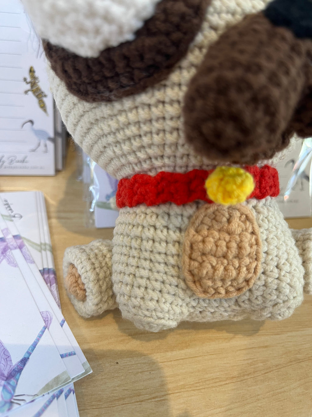 Suzie's Sunshine Dolls Pig the Pug crochet toy, beige with red collar and yellow bell, brown ears and markings.