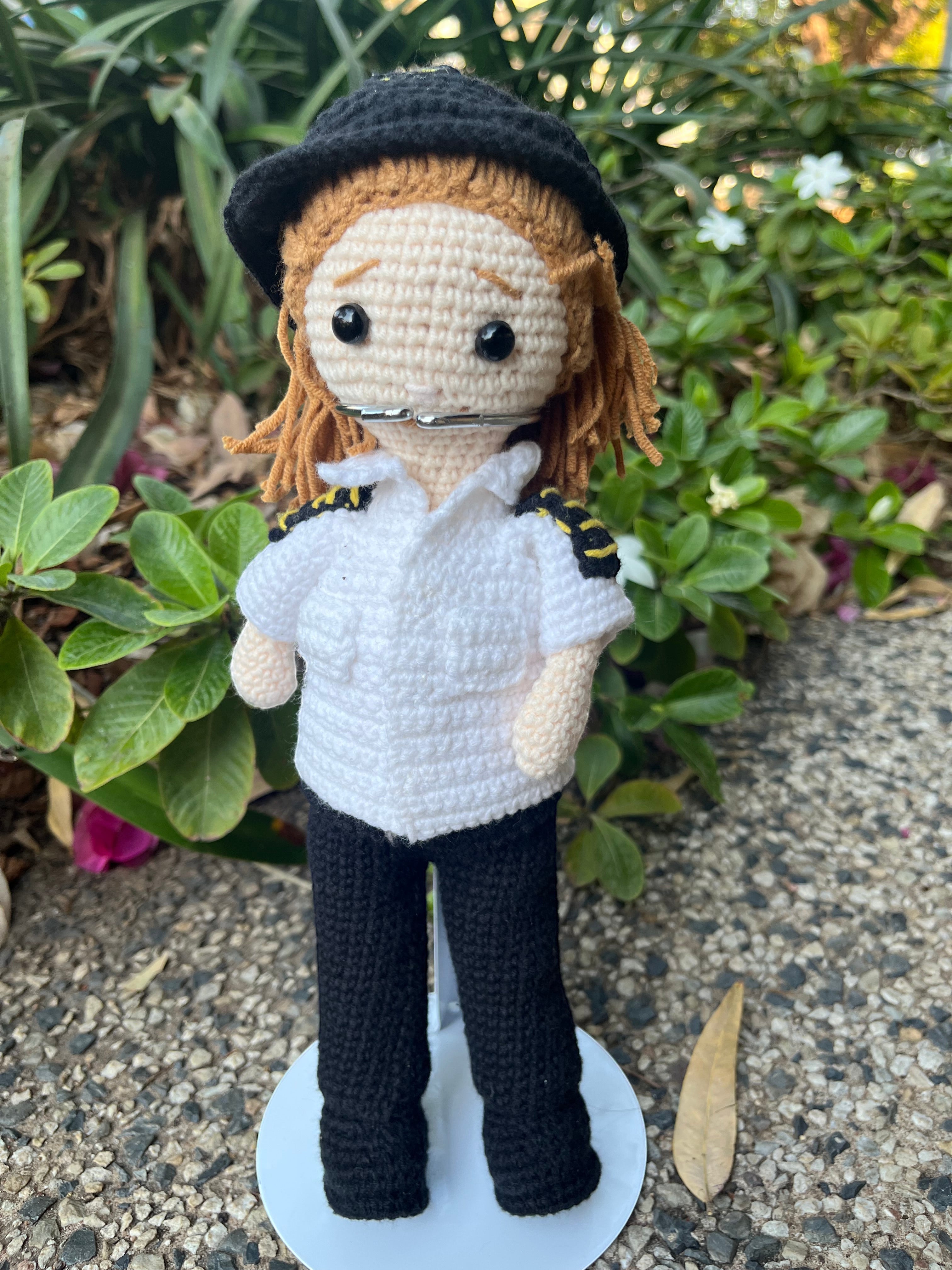 Suzie's Sunshine Dolls handmade crochet pilot doll in white shirt, black pants, and hat. Features yellow shoulder stripes.