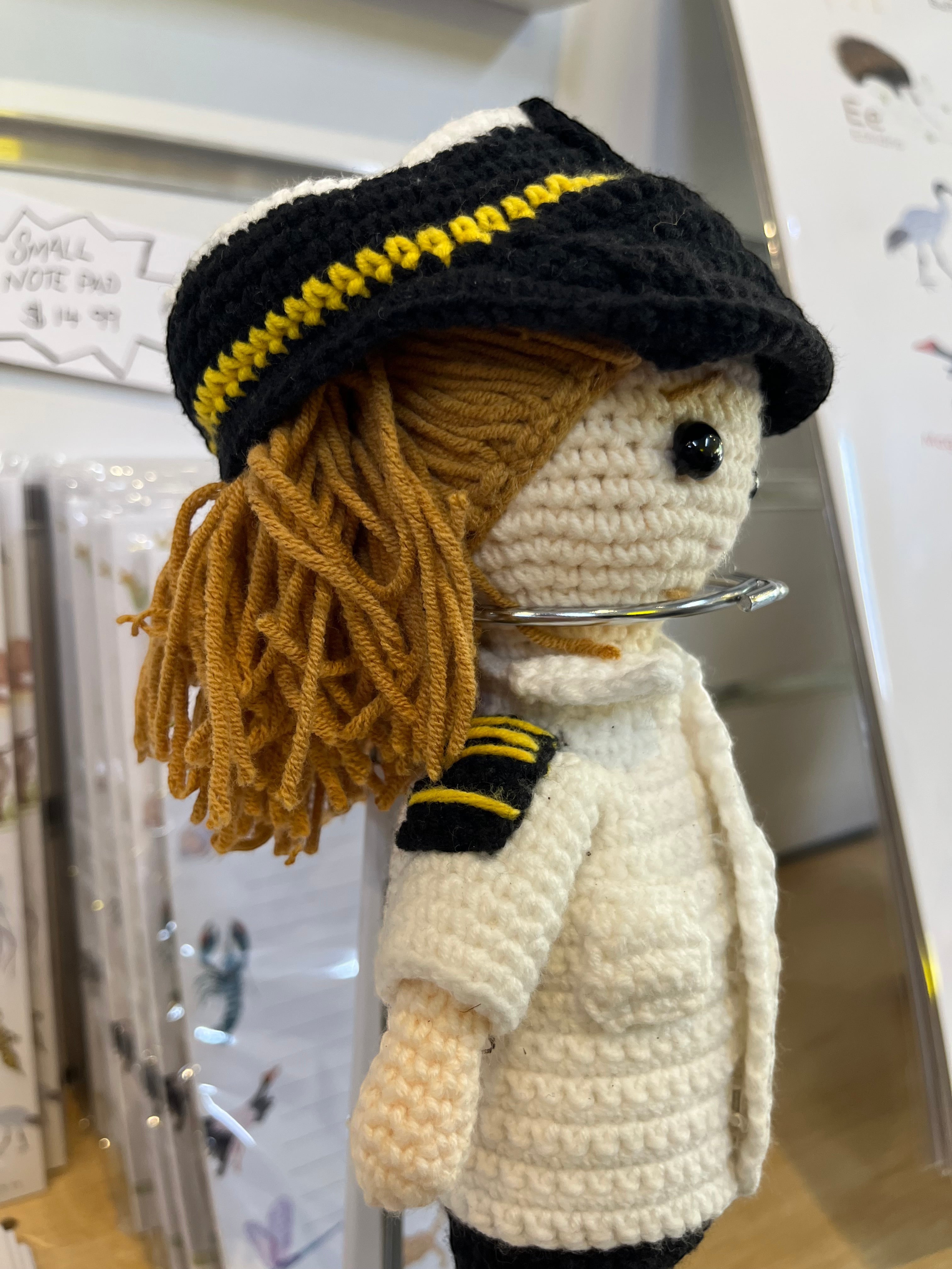 Suzie's Sunshine Dolls handmade crochet pilot doll in uniform with yellow-striped hat and shoulder epaulets.