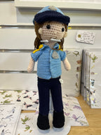 Suzie's Sunshine Dolls crocheted police officer doll in blue uniform with cap and badge. Handmade yarn toy, 28-30cm tall.