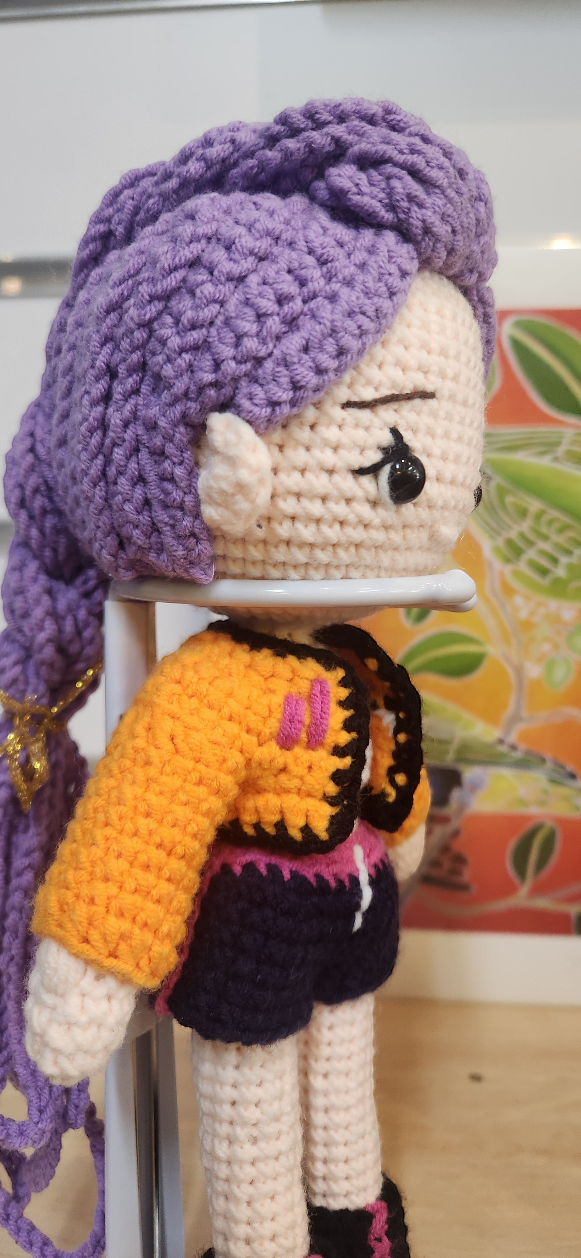 Suzie's Sunshine Dolls Rumi K-Pop Demon Hunter amigurumi doll with purple hair, orange jacket, and dark shorts.