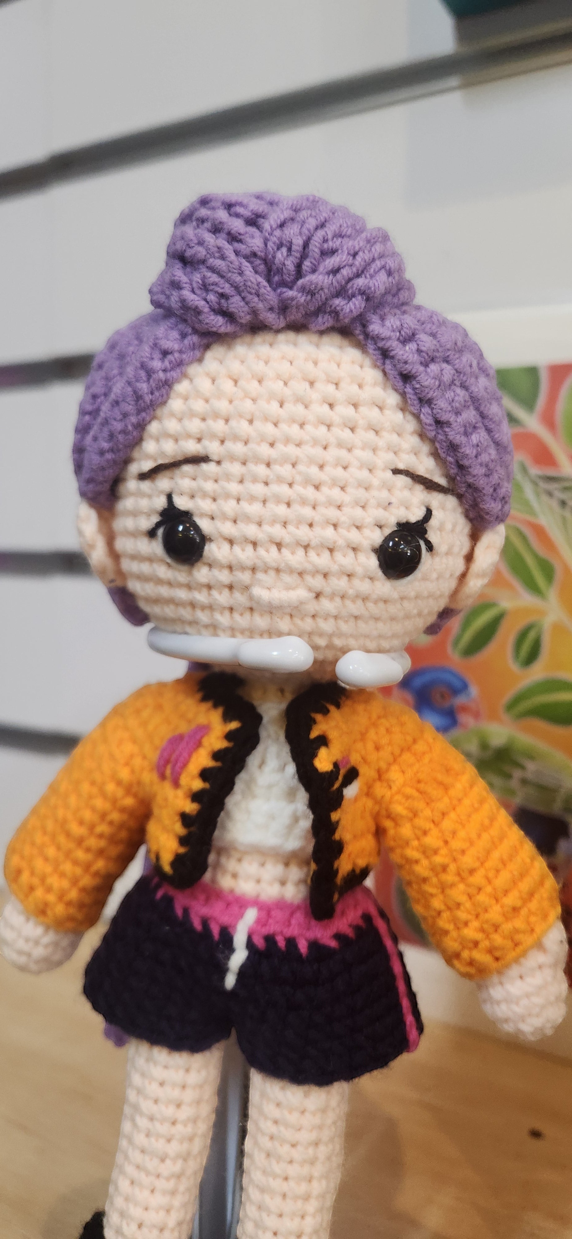 Suzie's Sunshine Dolls Rumi K-Pop Demon Hunter amigurumi doll with lilac hair, black eyes, orange jacket, and black shorts.