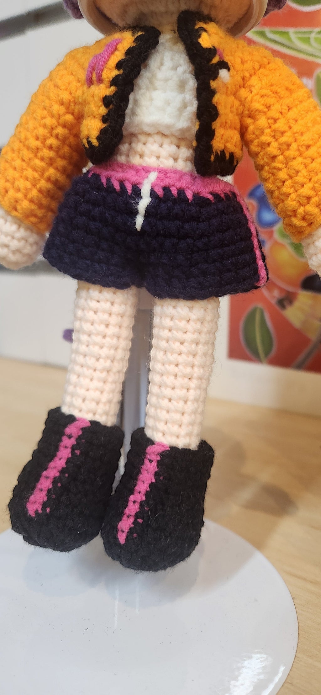 Suzie's Sunshine Dolls Rumi K-Pop Demon Hunter amigurumi doll in orange jacket, white top, navy shorts, and black boots with pink accents.