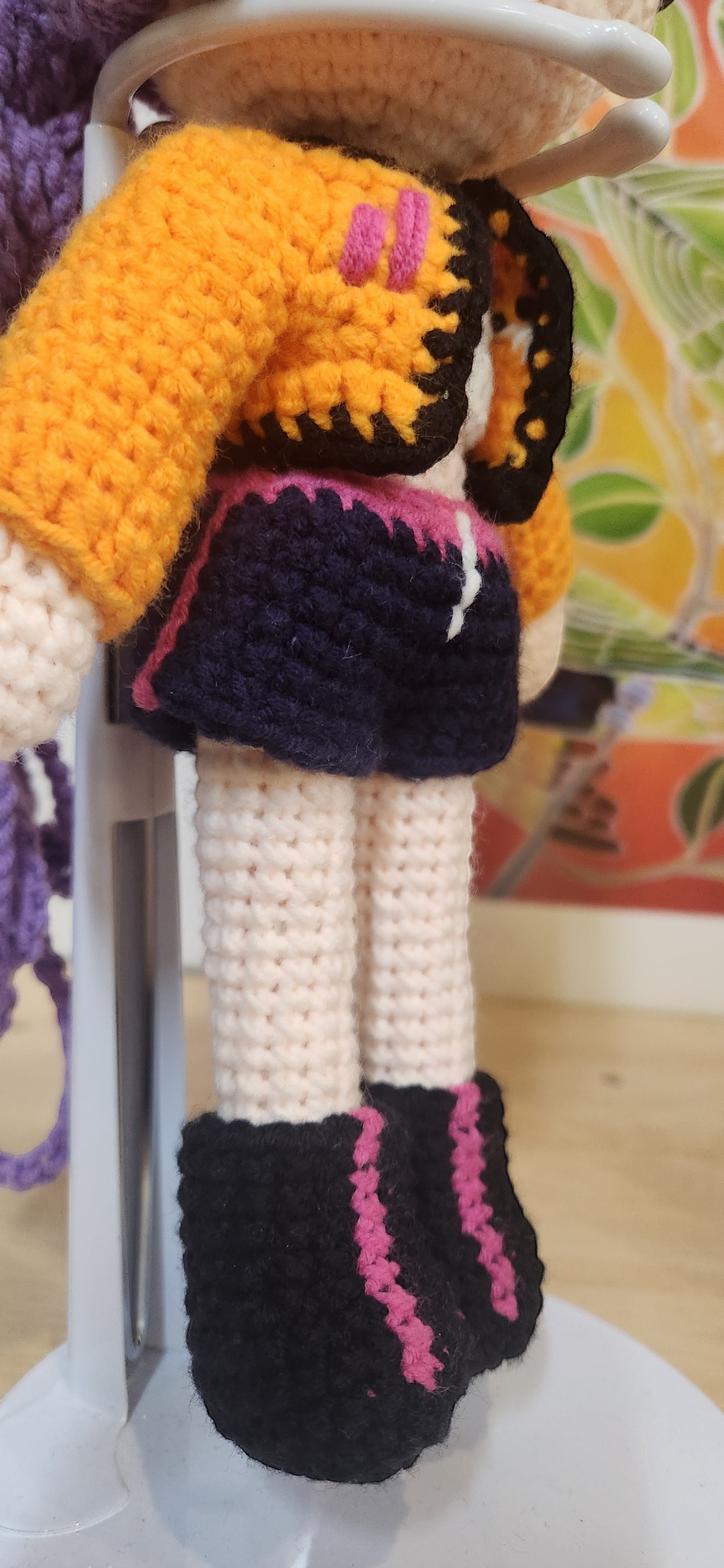 Suzie's Sunshine Dolls Rumi K-Pop Demon Hunter amigurumi doll in orange jacket, navy skirt, and black boots with pink trim.