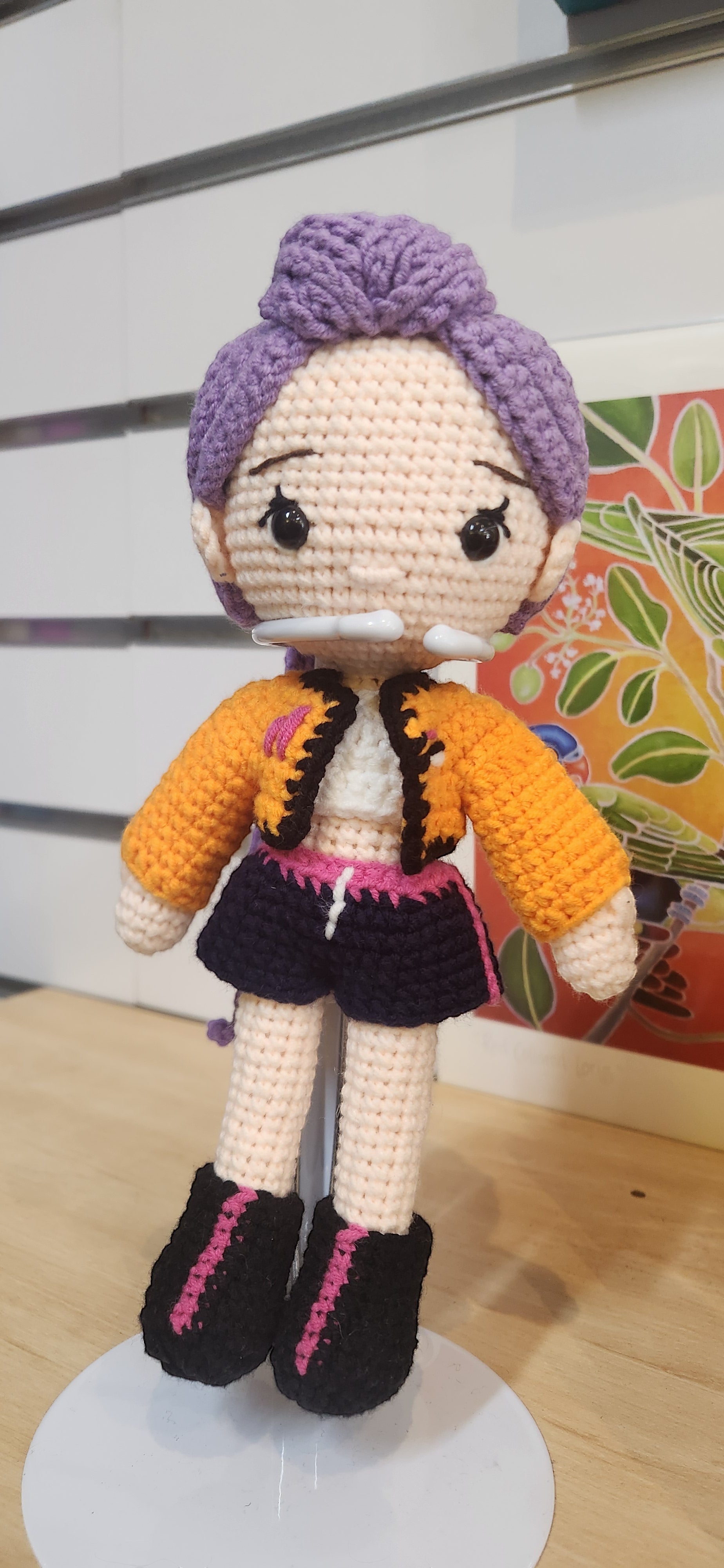 Suzie's Sunshine Dolls Rumi K-Pop Demon Hunter amigurumi doll with purple hair, orange jacket, and black shorts.