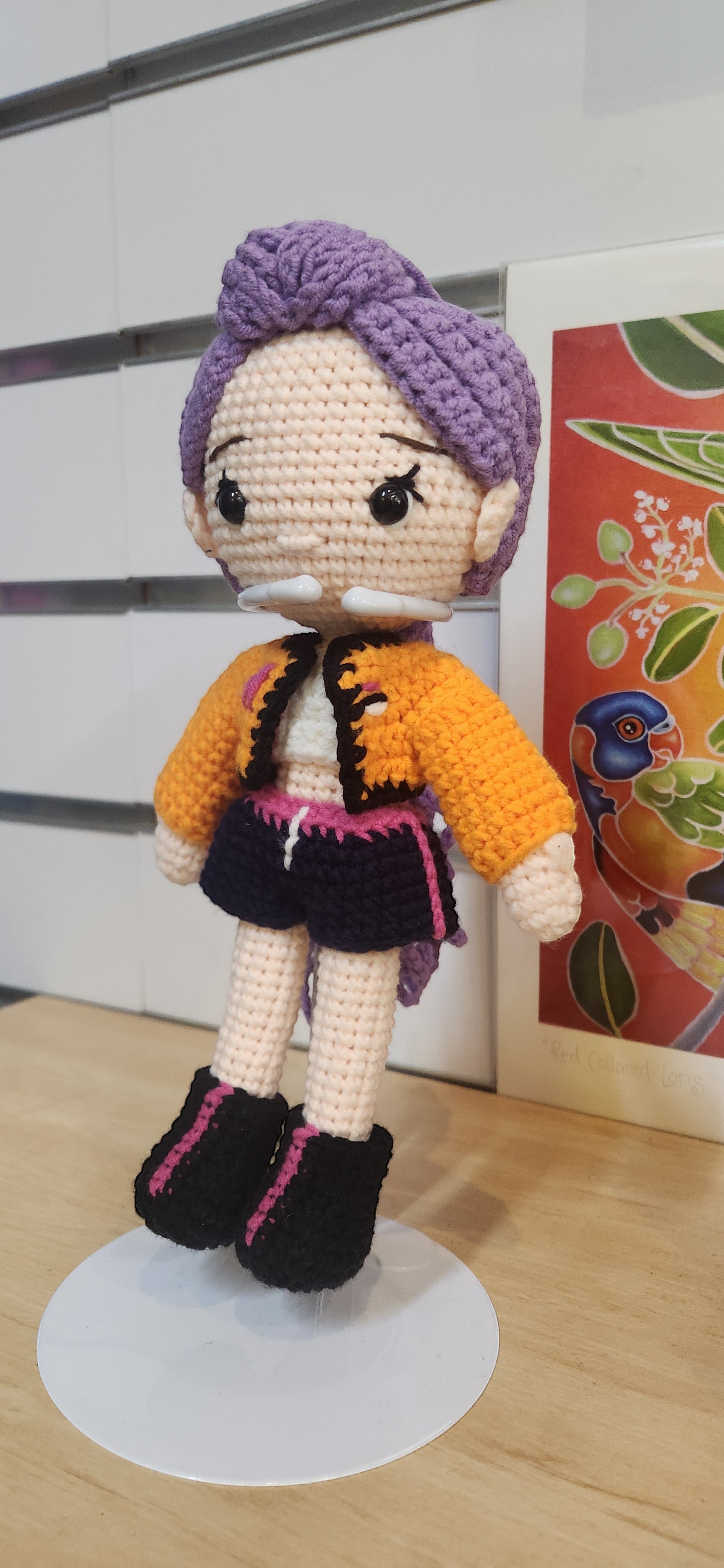 Suzie's Sunshine Dolls Rumi K-Pop Demon Hunter amigurumi doll with purple hair, orange jacket, and black shorts.