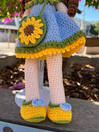 Suzie's Sunshine Dolls Sophie, a crocheted doll in a blue dress with yellow and green trim, yellow shoes with blue bows, and a sunflower purse.