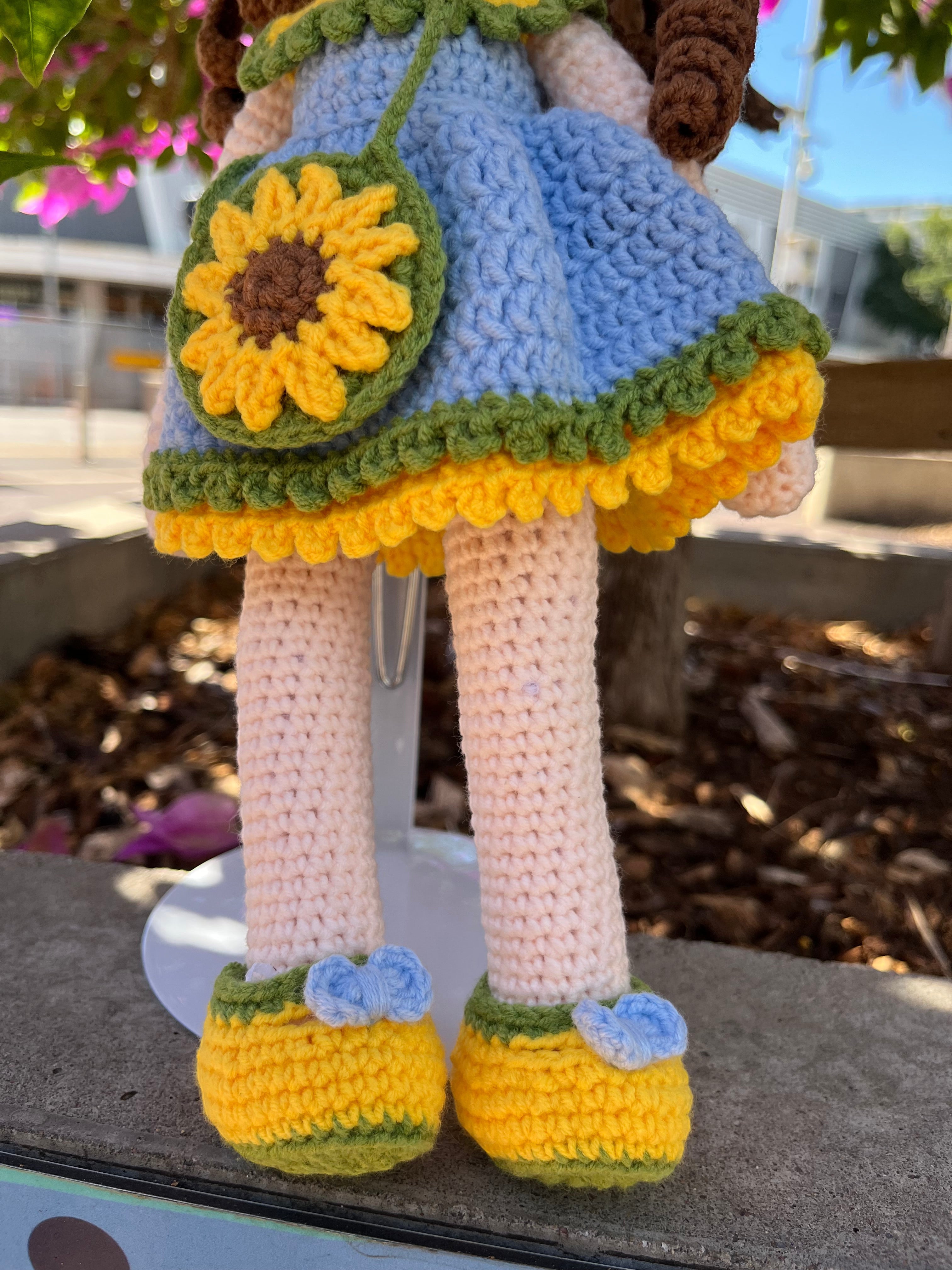 Suzie's Sunshine Dolls Sophie, a crocheted doll in a blue dress with yellow and green trim, yellow shoes with blue bows, and a sunflower purse.