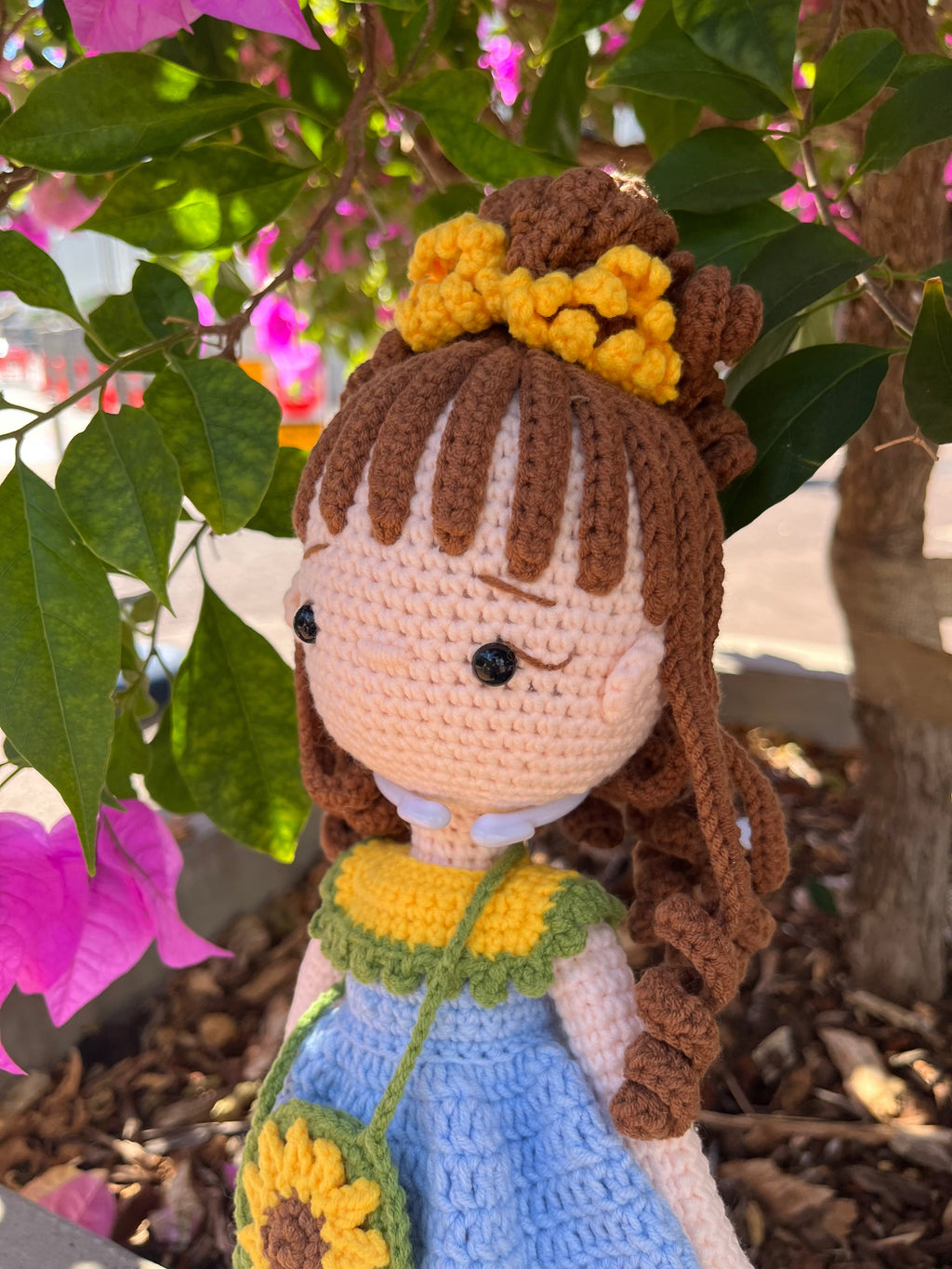 Suzie's Sunshine Dolls Sophie, a crocheted doll in a blue dress with yellow and green trim, brown curly hair, and a sunflower purse.