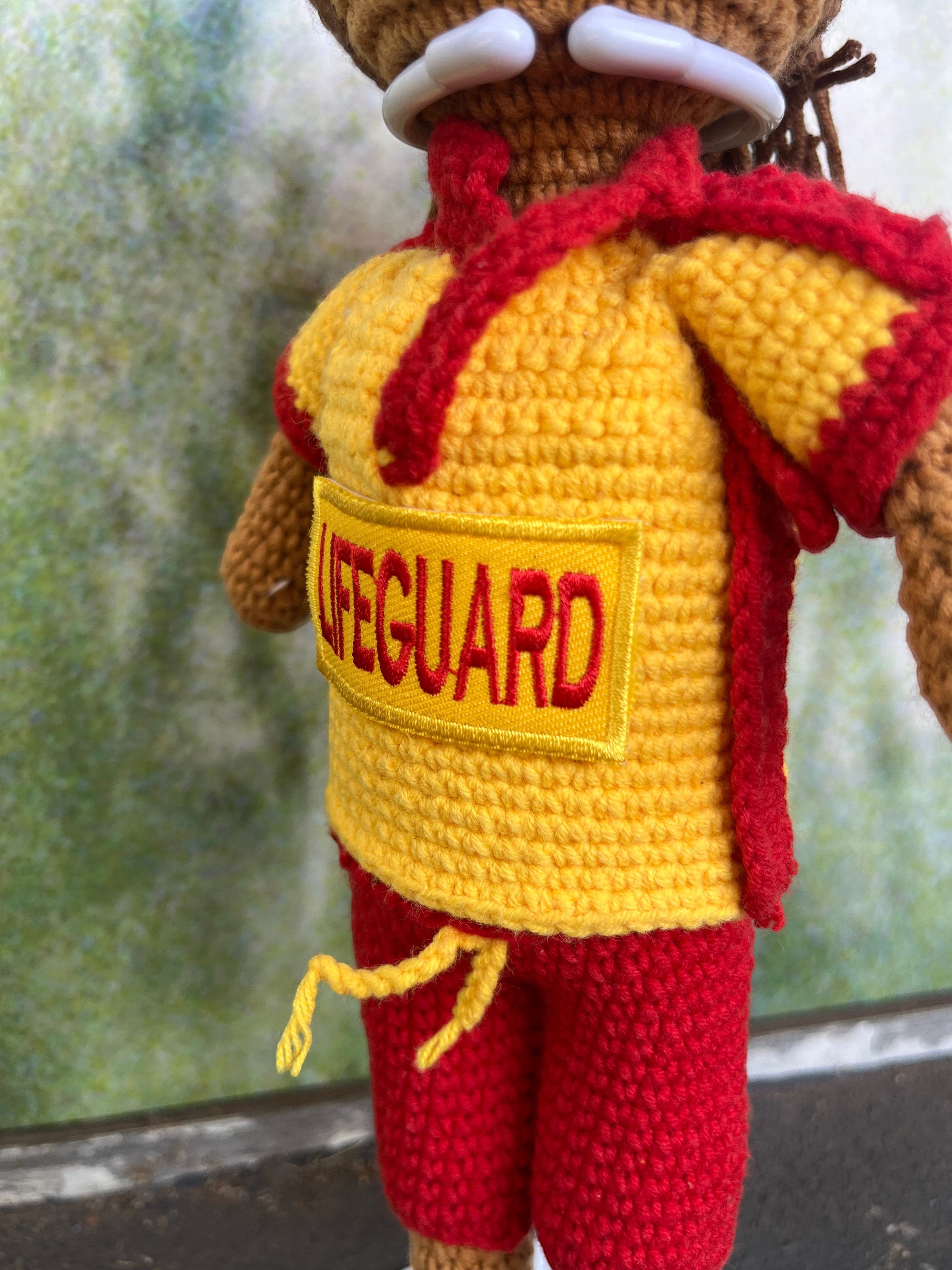 Suzie's Sunshine Dolls Surf Lifesaver doll in red shorts and yellow rashie with red trim and 'LIFEGUARD' patch. Handmade crochet.