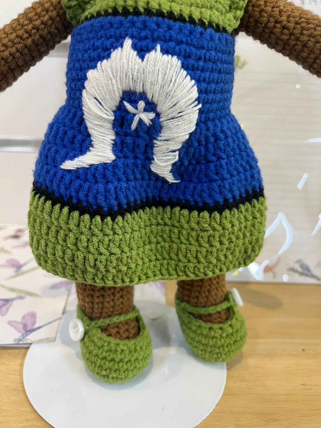Suzie's Sunshine Dolls Leilani, a handmade crochet doll with long black hair, wearing a blue dress with white Dhari and star, and green shoes.