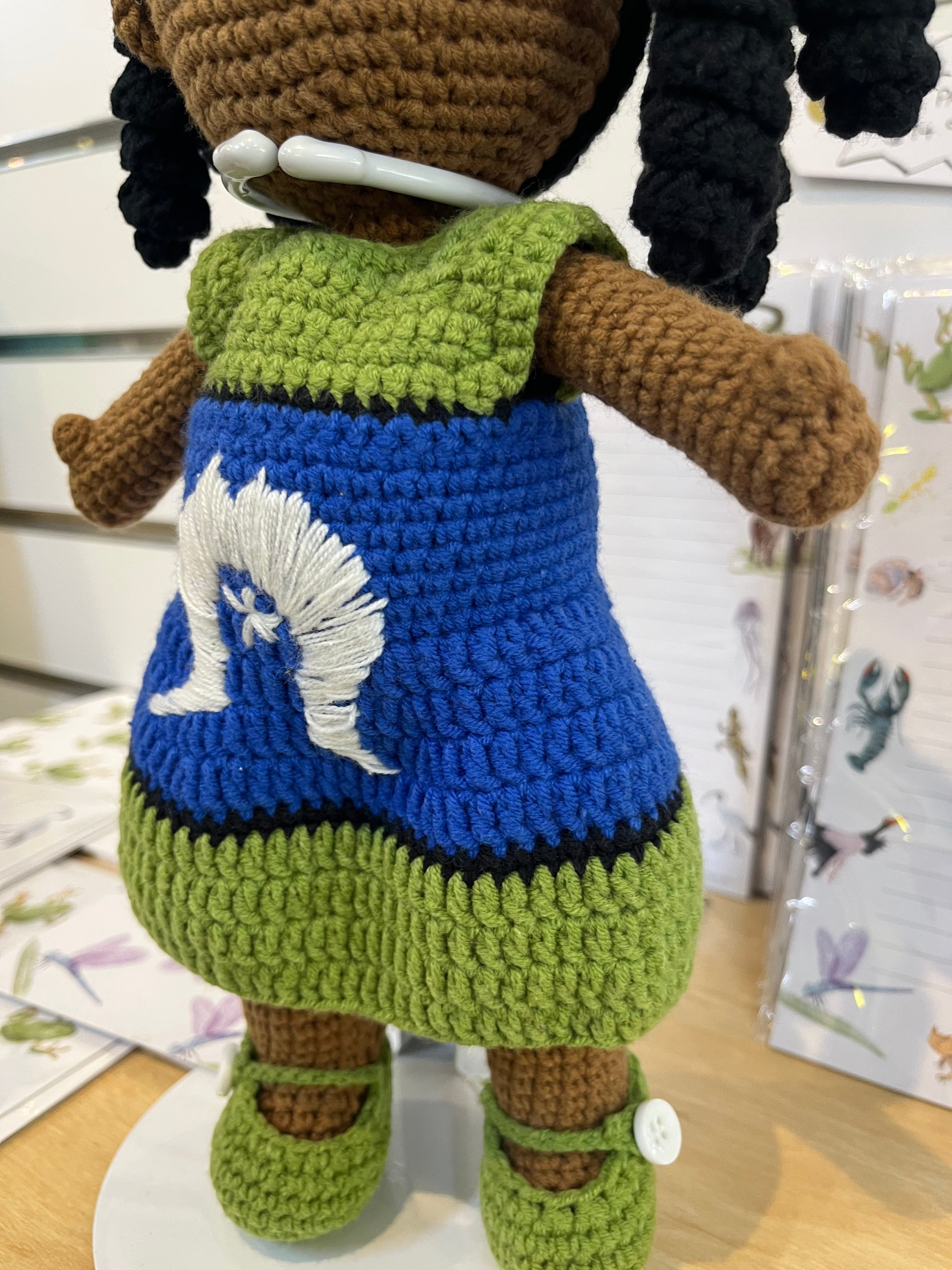Suzie's Sunshine Dolls handmade crochet doll with long black hair, wearing a blue dress with white embroidery and green trim, representing Torres Strait Islander culture.