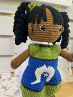 Suzie's Sunshine Dolls handmade crochet doll with long black curly hair, wearing a green and blue dress with white embroidery representing the Torres Strait Islander flag.