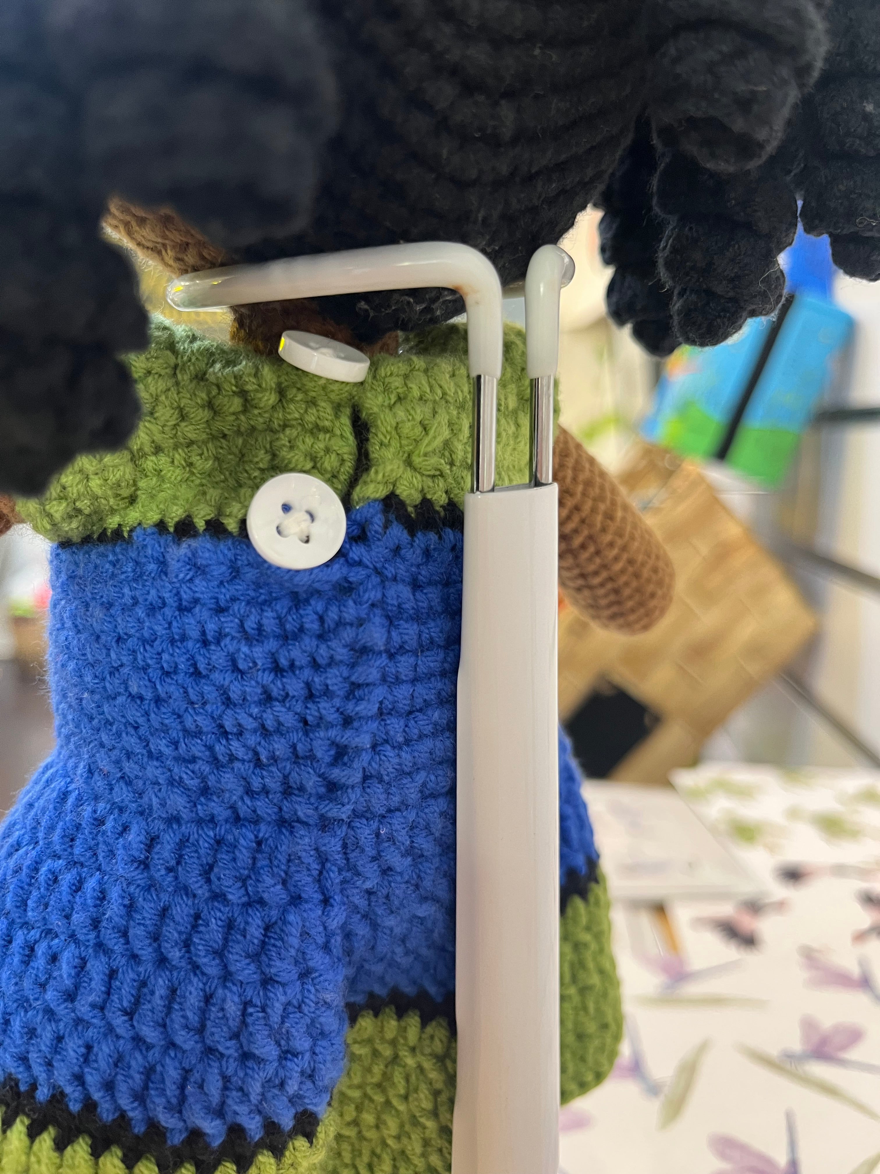 Suzie's Sunshine Dolls Leilani, a handmade Torres Strait Islander doll with long black curly hair and a crocheted flag dress in blue, green, and black.