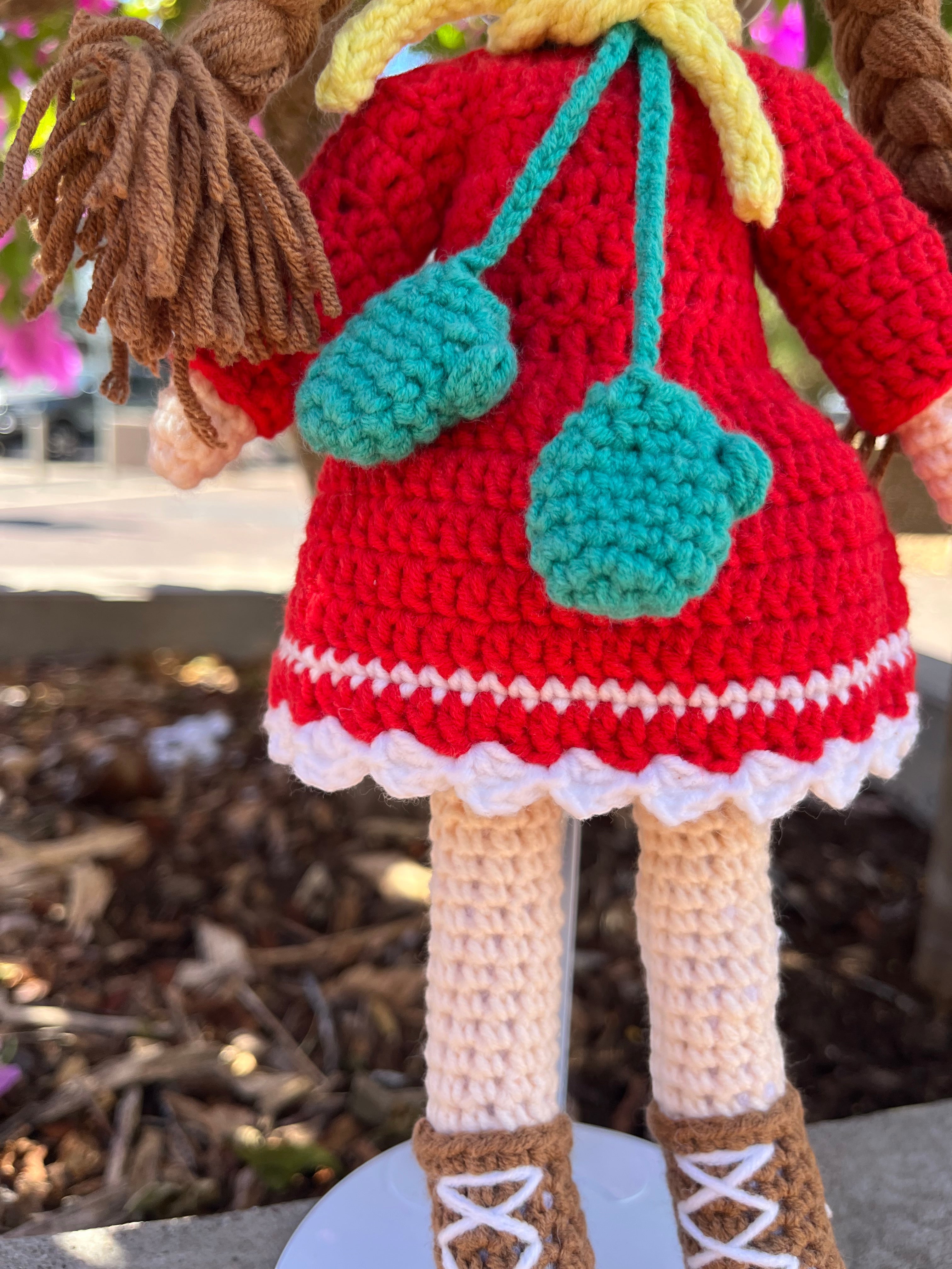 Suzie's Sunshine Dolls Zoey doll in red crocheted dress, yellow beanie, brown boots, and turquoise scarf.